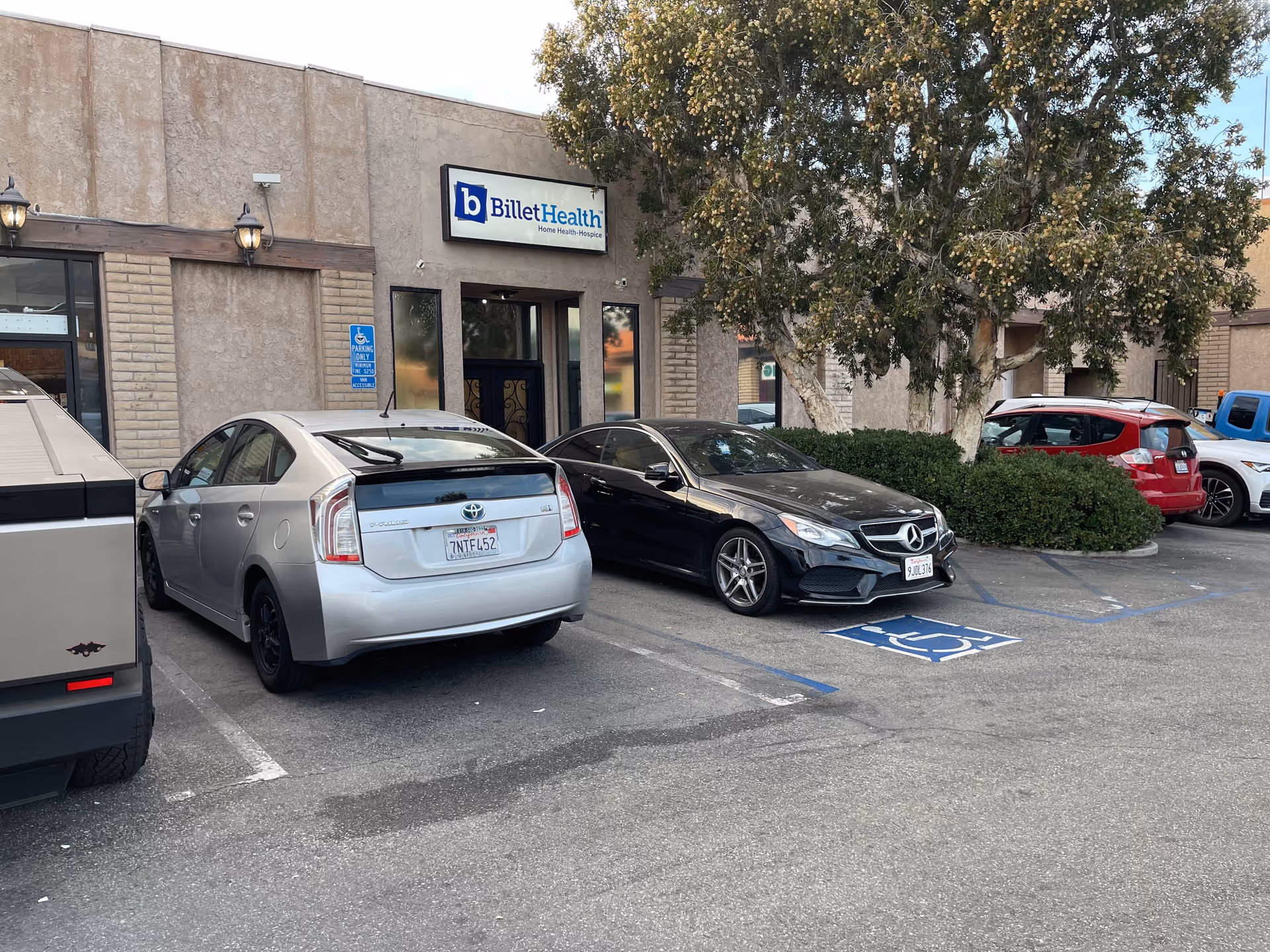 Exterior view of Billet Health front with sign, parked cars, and trees nearby.