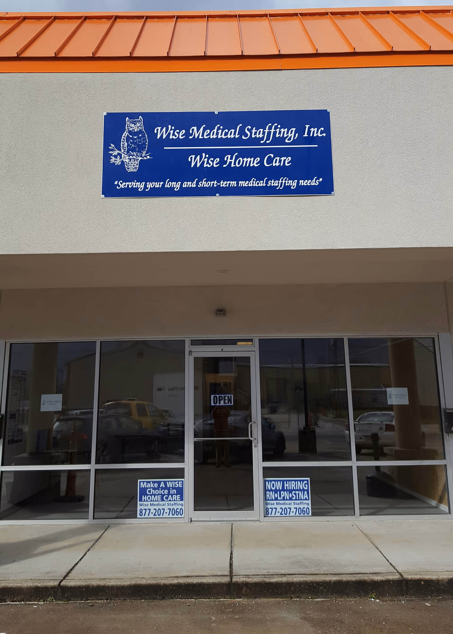 Blue sign reading Wise Medical Staffing, Inc. on a beige building exterior with glass doors.
