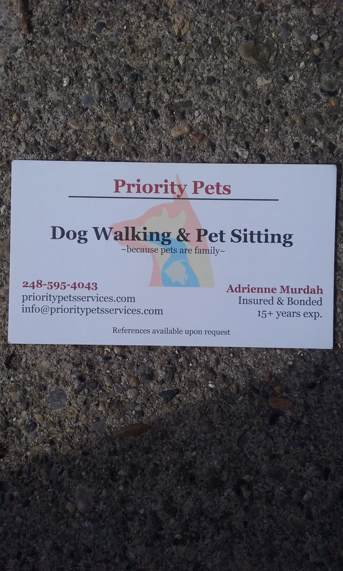 White business card on concrete advertising Priority Pets dog walking and pet sitting services.