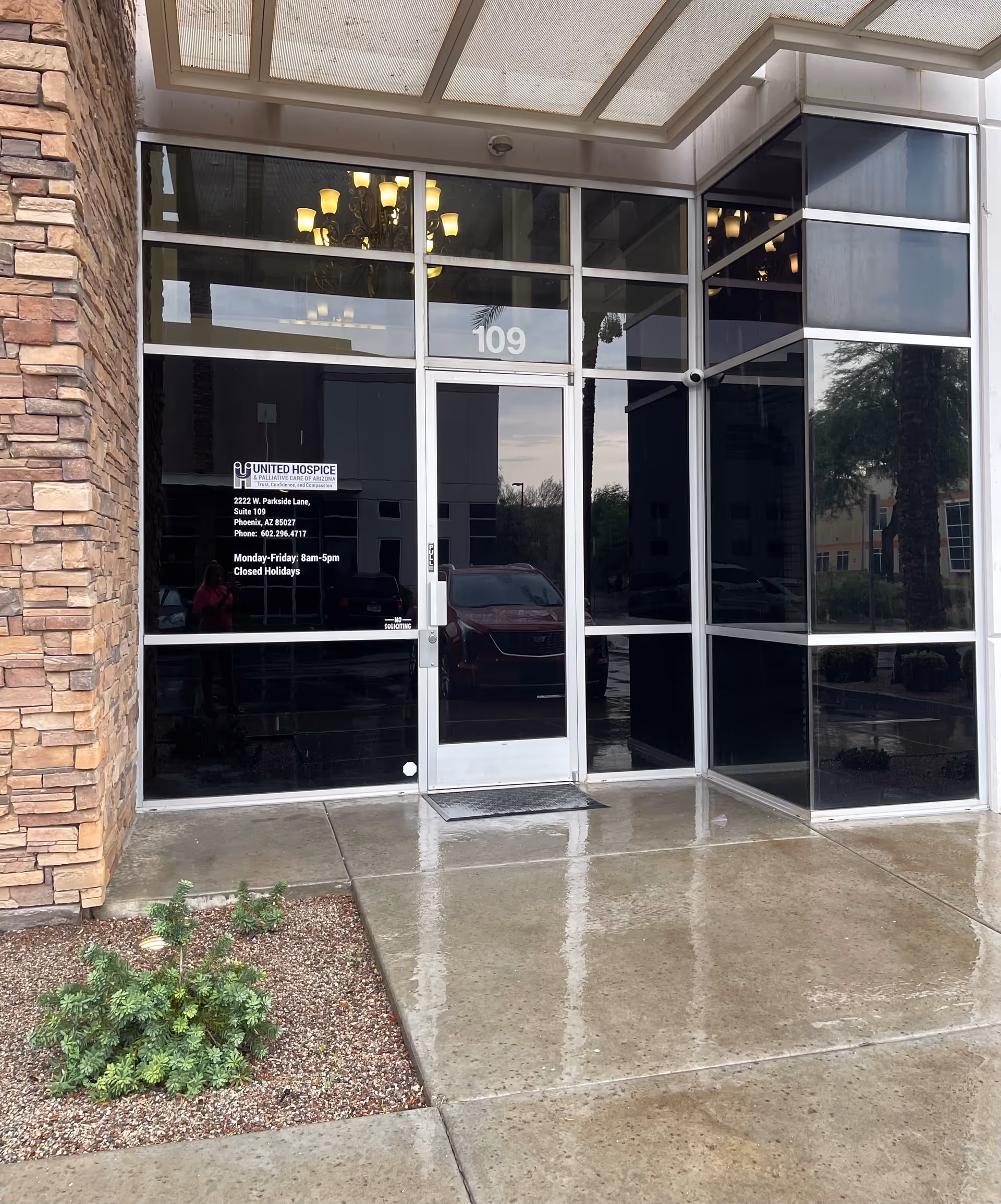 Glass storefront entrance with 109, stone-clad exterior, and reflected interior chandelier.