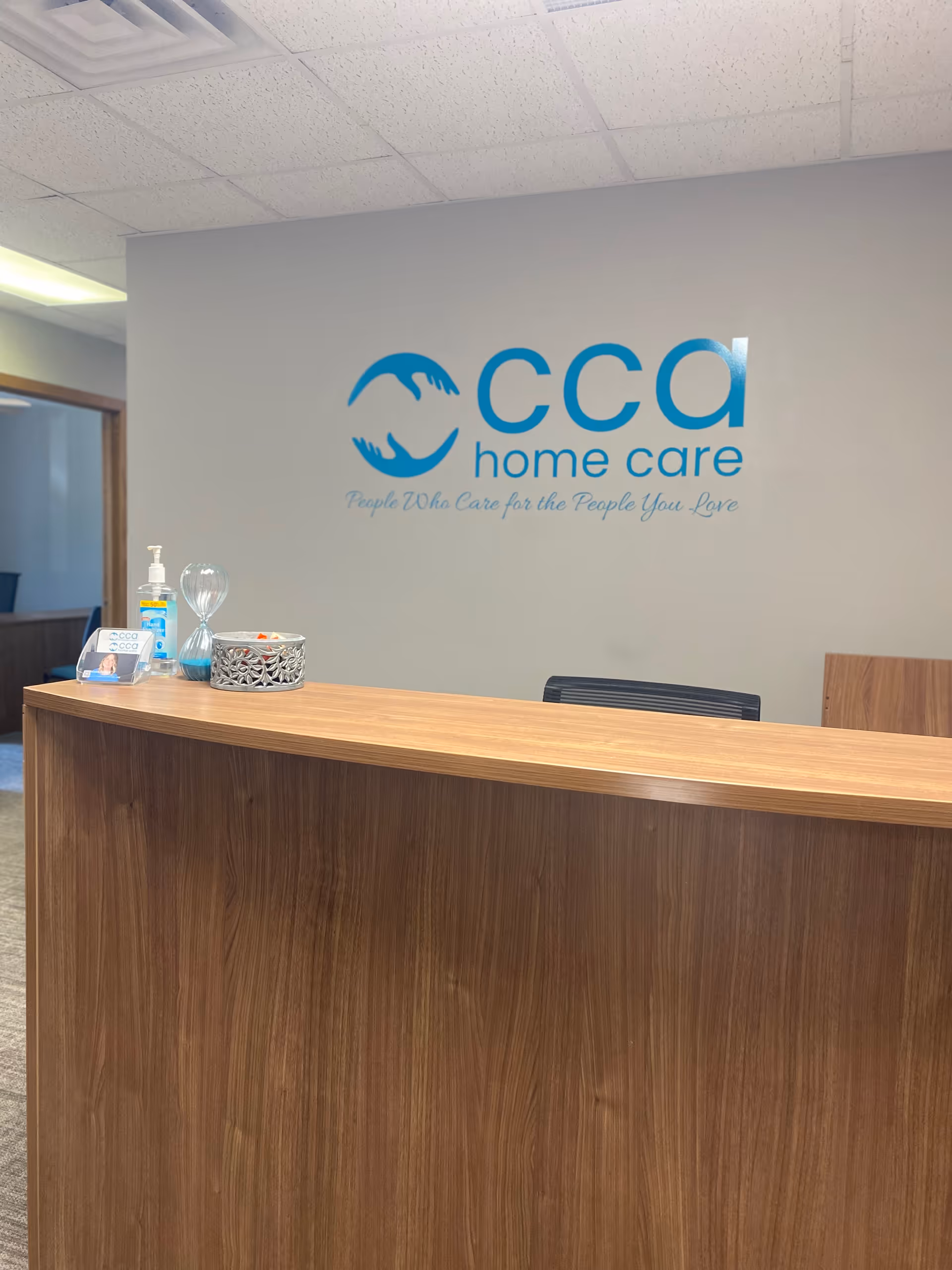 Reception desk in a facility lobby with a blue CCA Home Care logo.