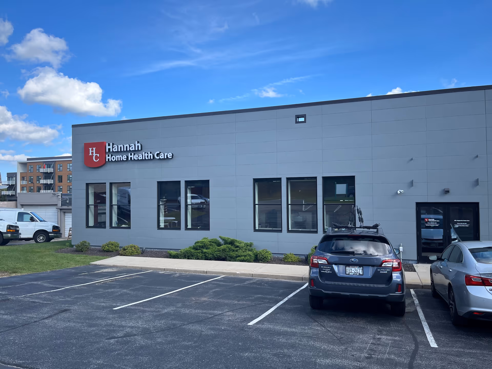 Modern gray building with Hannah Home Health Care sign and a small parking lot.