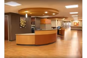 Curved wooden reception desk in a spacious, well-lit senior living lobby.