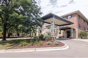 Greentree Glen front entrance with a covered drop-off, brick building, and manicured landscaping.