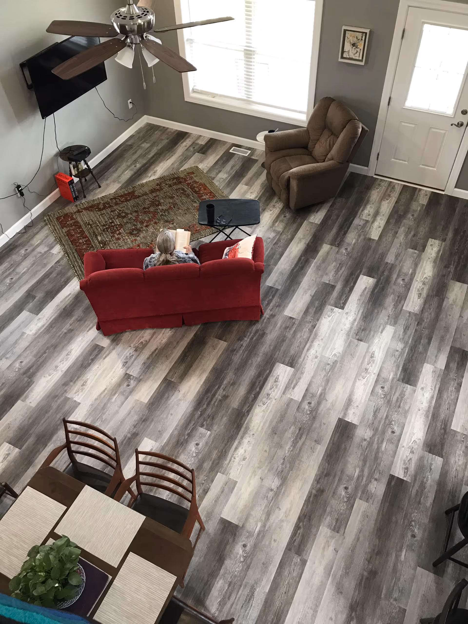 Overhead view of a living room with red sofa, recliner, dining area, and TV.