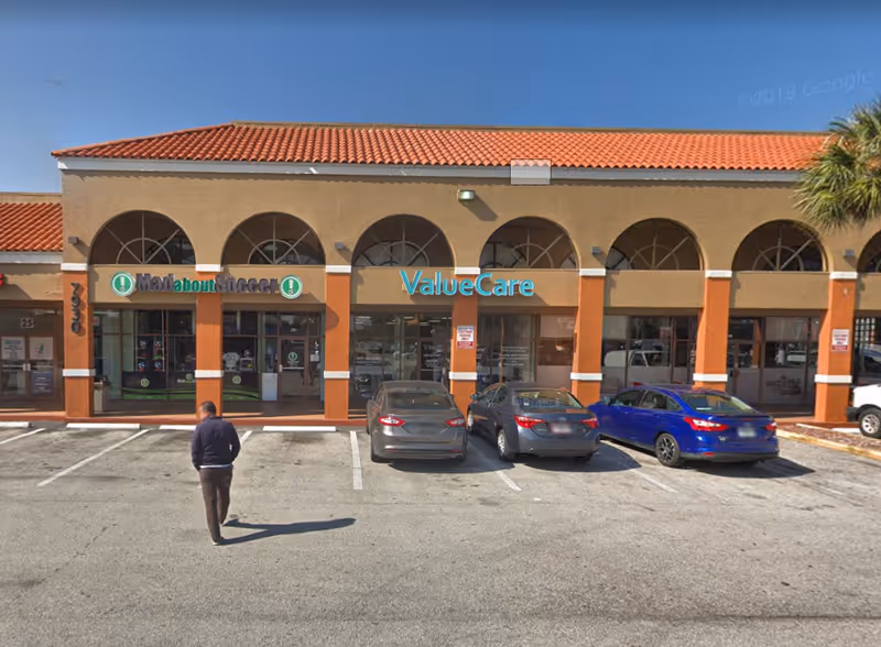 ValueCare storefront in a strip mall with parked cars and a pedestrian.