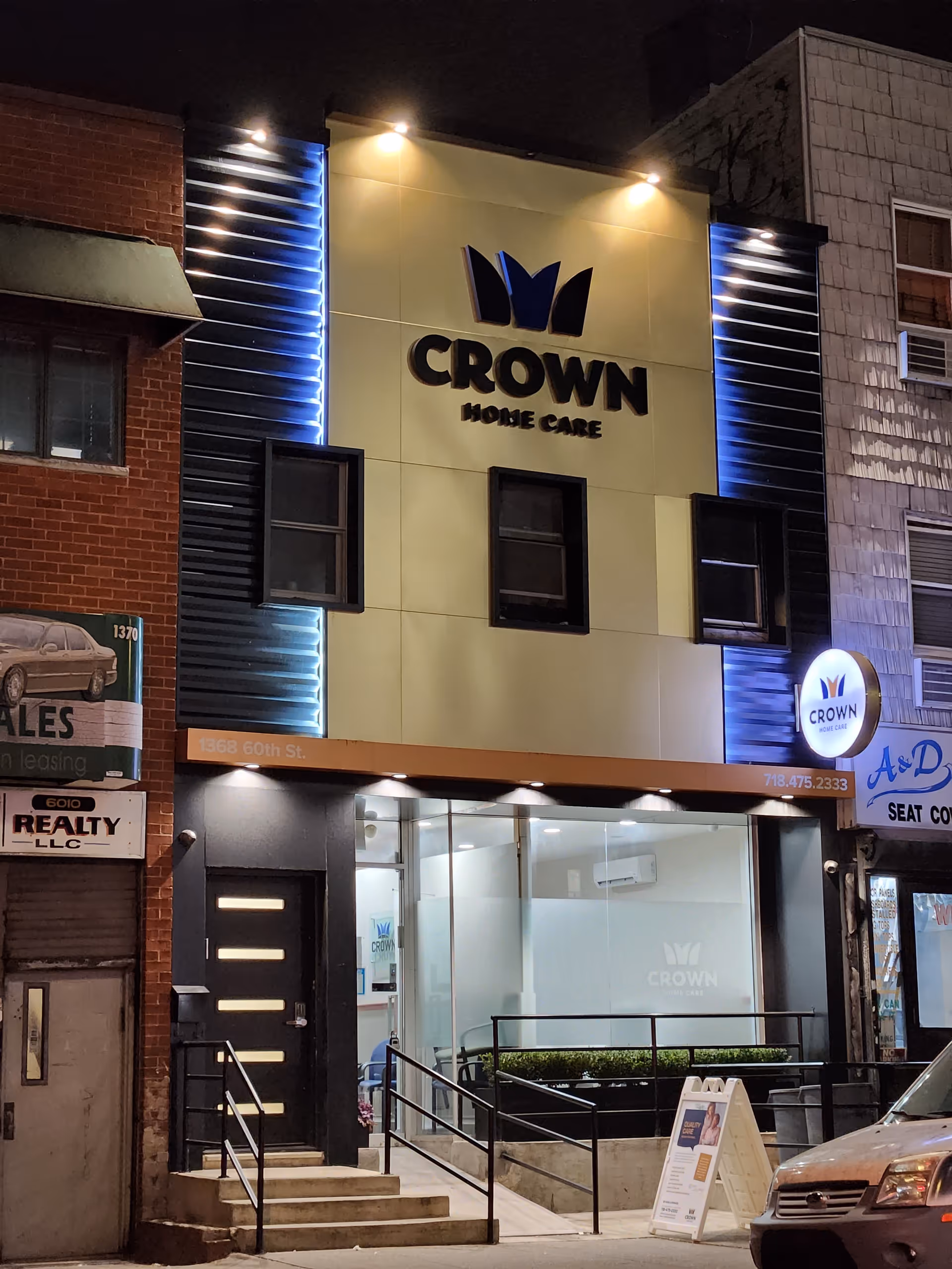 Nighttime storefront of Crown Home Care with illuminated sign and glass entrance on a city street.