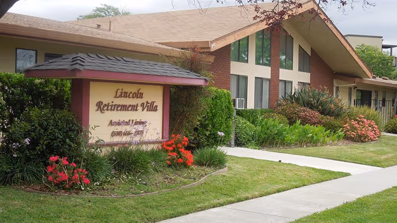 Exterior view of Lincoln Retirement Villa featuring the sign, greenery, and sidewalk.