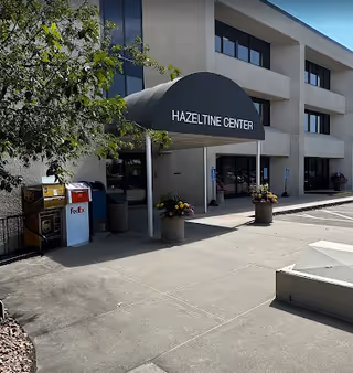 Exterior view of the Hazeltine Center entrance with a curved black canopy.