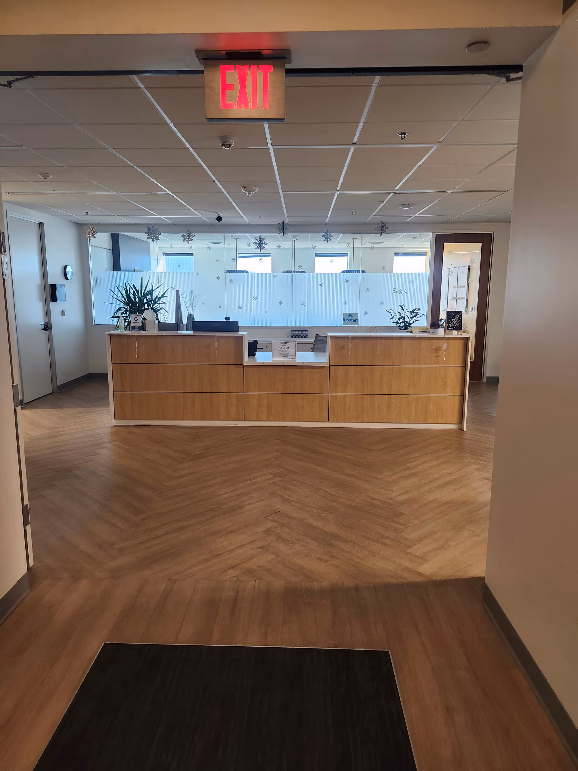 Indoor reception area with wooden counter, frosted glass divider, and an illuminated EXIT sign.