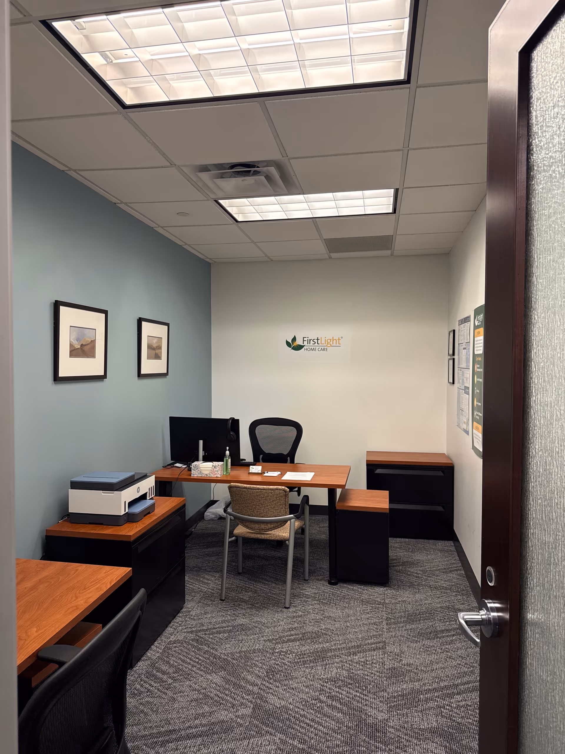 Office workspace in a FirstLight Home Care facility with desk, computer, and printer.