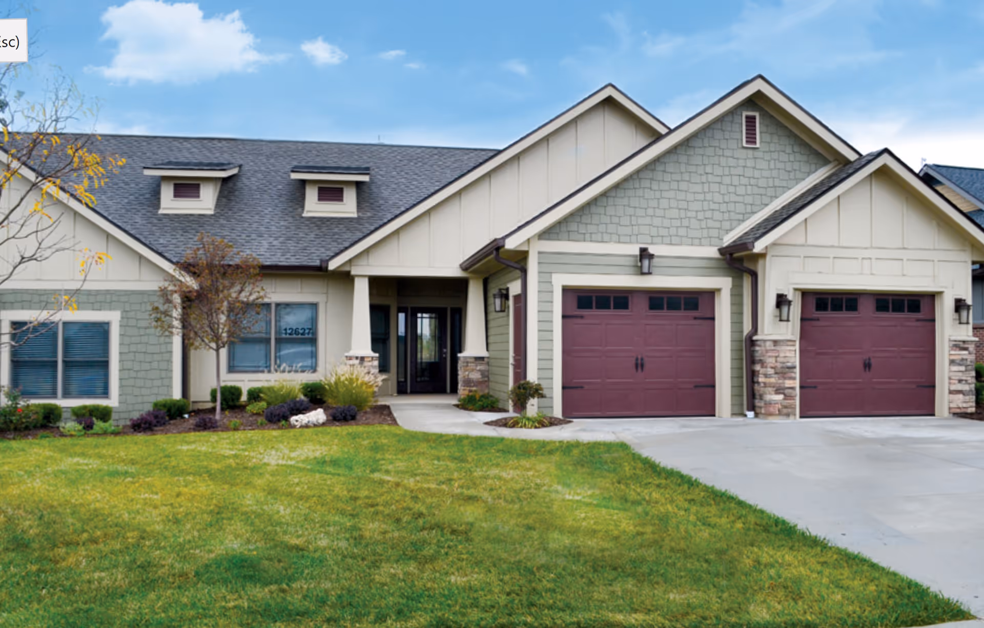 Exterior view of a senior living facility with a three-car garage and green lawn.