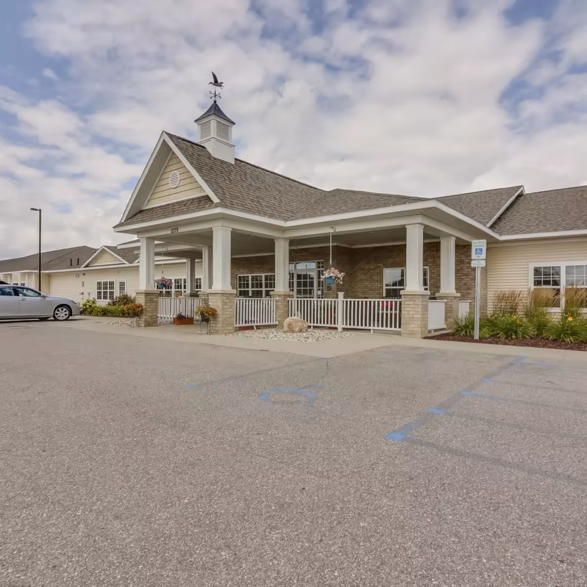 Front entrance of Crestwood Village Assisted Living and Memory Care, with a covered porch and parking.