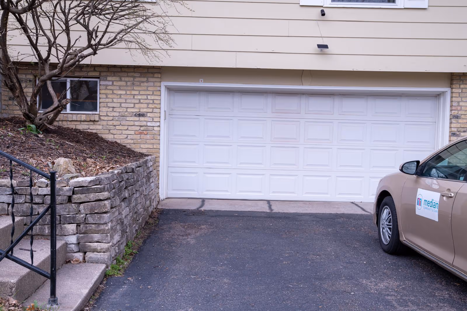 Exterior view of Median Care Assisted Living Facility with a closed garage door and a car.