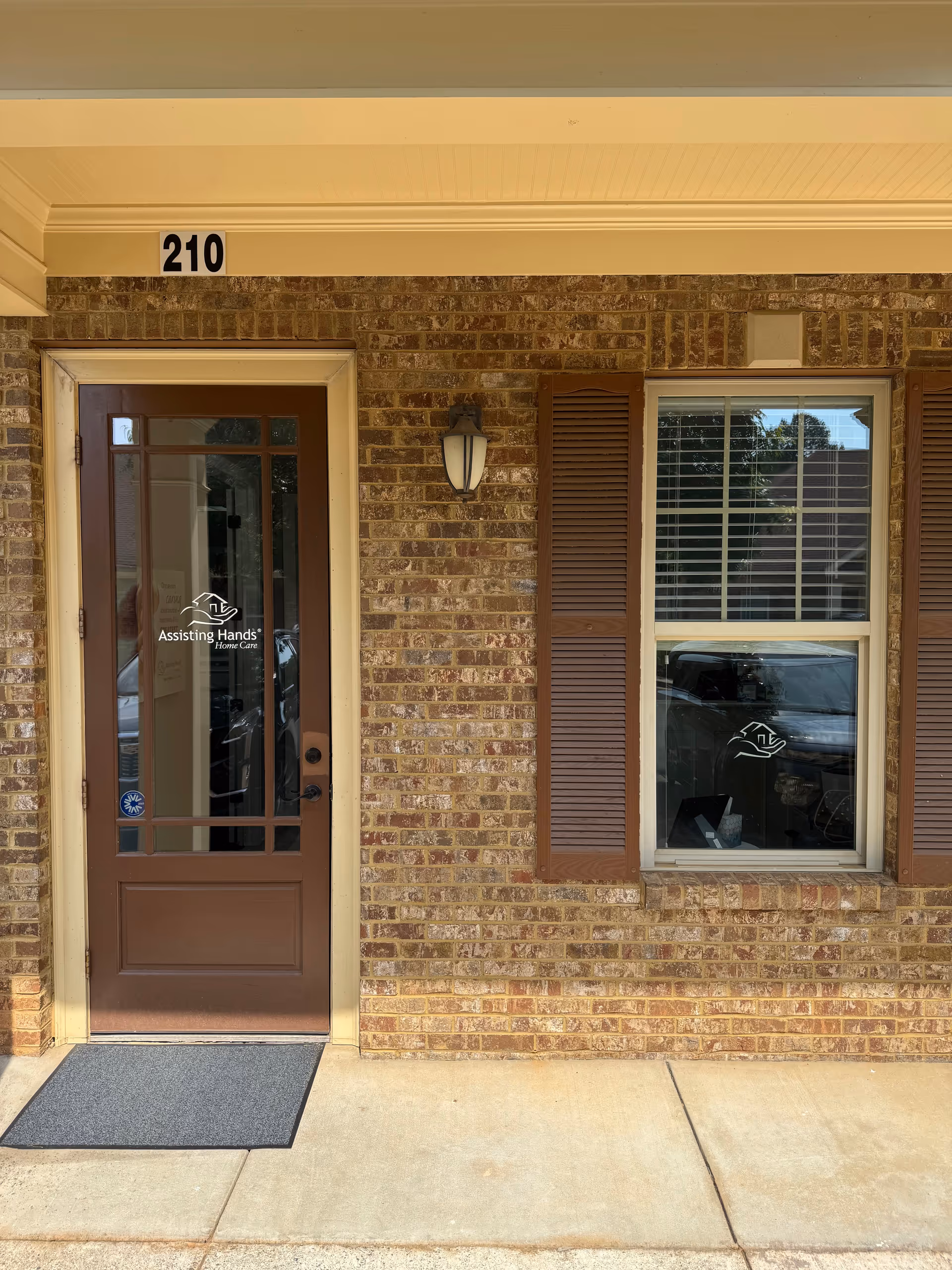 This brick exterior shows a door and window at address 210 for Assisting Hands entry.