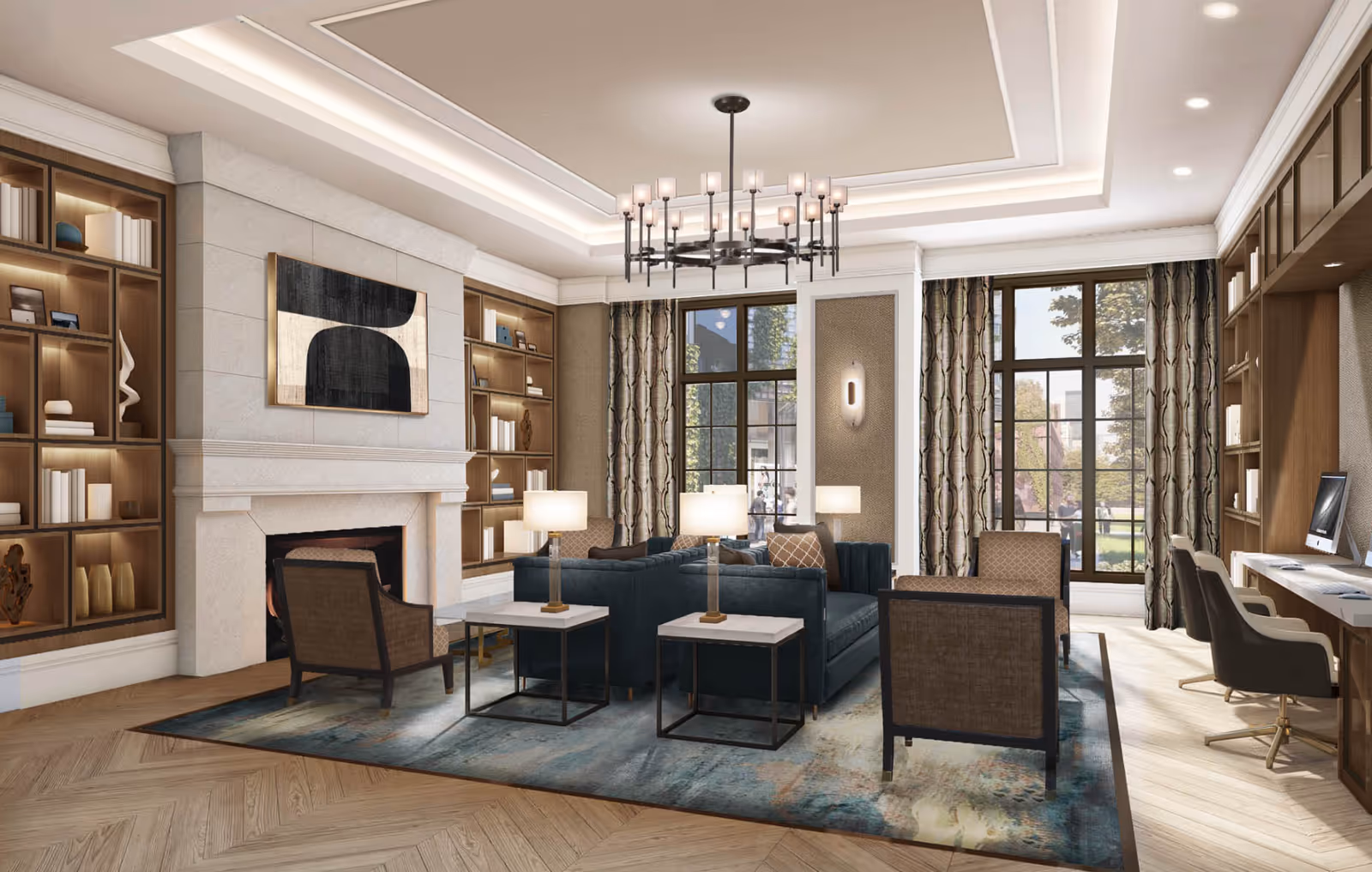 A spacious and elegant living room with a large blue sectional sofa, two armchairs, and two side tables with lamps. The room features a fireplace with a modern abstract painting above it, built-in wooden bookshelves with decorative items, large windows with patterned curtains, and a chandelier hanging from a tray ceiling. There is also a desk area with computers and chairs along one wall.