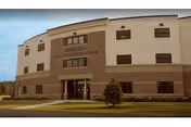 Exterior view of a three-story building with a beige and brown facade, labeled 'Eastern Star Senior Care Center' above the entrance. The building is surrounded by a lawn with a small tree in front.