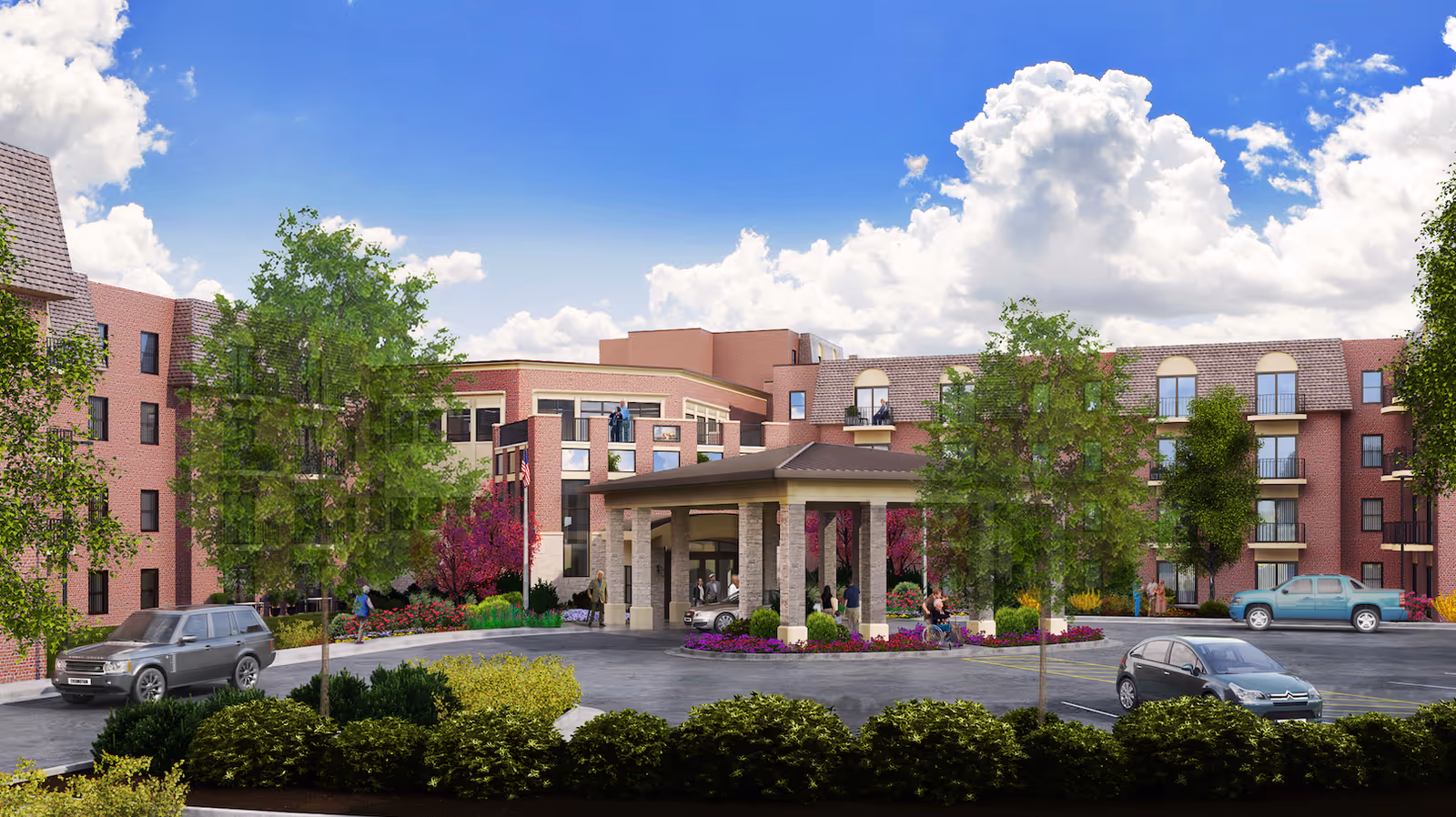 Exterior view of Kingswood Senior Living Community showing a multi-story brick building with balconies, a covered entrance with stone pillars, several trees and shrubs, and a parking area with cars under a partly cloudy blue sky.