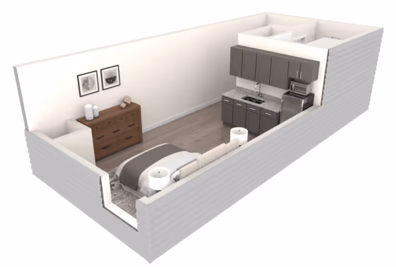 3D floor plan of a studio apartment featuring a sleeping area with a bed, two bedside tables with lamps, a wooden dresser with decorative items and framed pictures above it, and a kitchenette with dark cabinets, a sink, microwave, and refrigerator.