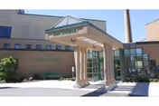 Entrance of Guthrie Cortland Medical Center showing a covered drop-off area supported by columns, with the building facade and windows in the background under a clear sky.