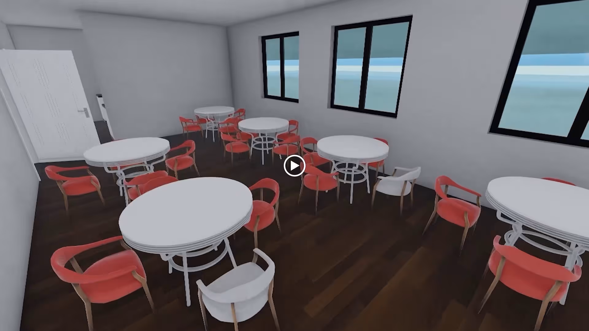 Interior view of a dining room with multiple round white tables surrounded by red and white chairs. The room has dark wooden flooring, white walls, and three large windows letting in natural light.