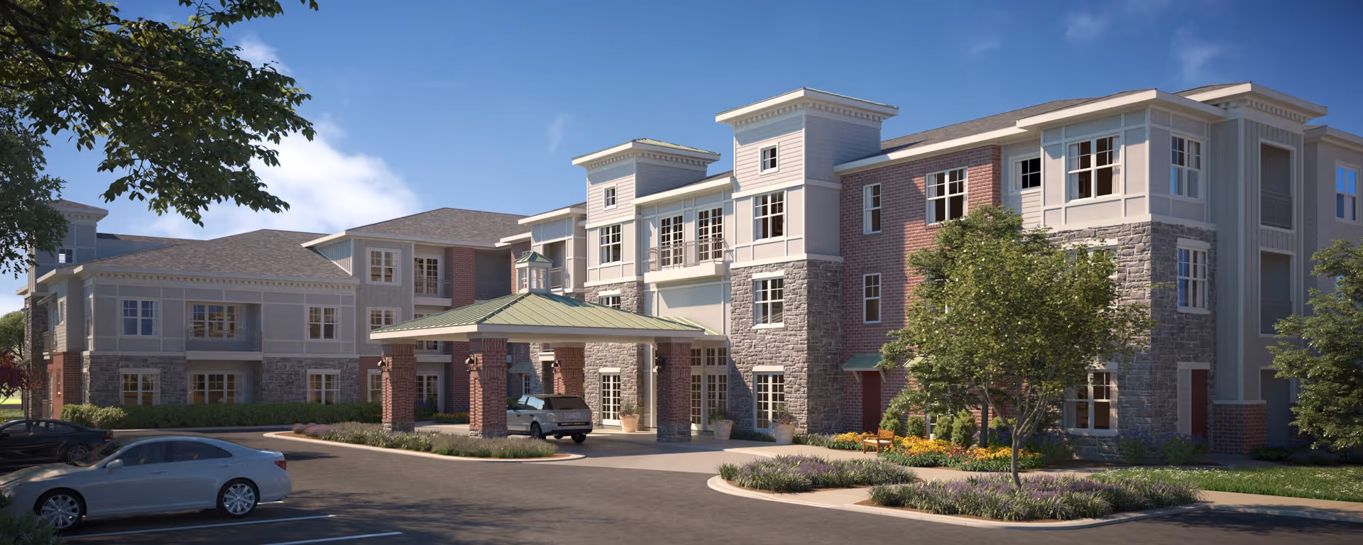 Exterior view of a three-story senior living facility building with a covered entrance, surrounded by trees, shrubs, and parked cars under a blue sky.