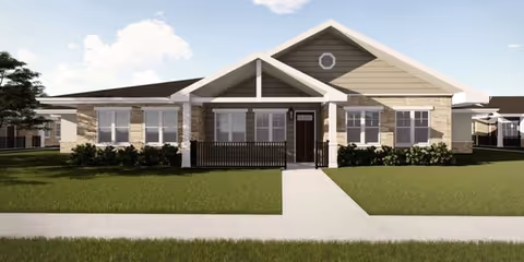 Front exterior view of a single-story residential building with a gabled roof, multiple windows, a central entrance with a small covered porch, and a well-maintained lawn and sidewalk leading to the door.