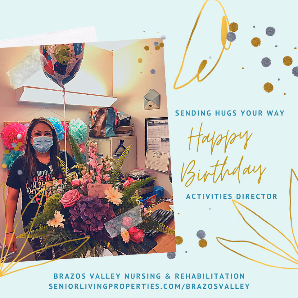 A woman wearing a face mask stands behind a large bouquet of flowers and a balloon in an office setting. The image includes a birthday greeting that says, 'Sending hugs your way. Happy Birthday Activities Director.' The background shows office supplies and decorations.
