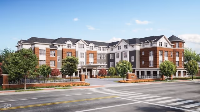 Exterior view of a large, multi-story senior living facility named Sunrise of Newton, featuring a combination of brick and light-colored siding, multiple windows, a covered entrance, landscaped greenery, and a clear blue sky.
