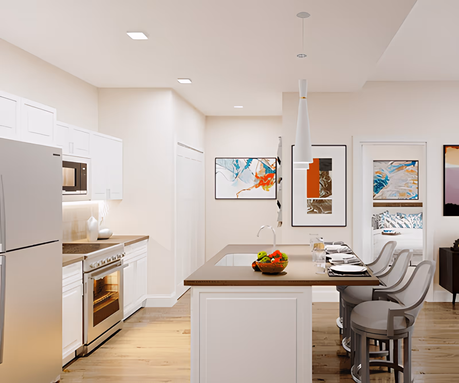 Modern kitchen with white cabinets, stainless steel refrigerator and oven, a kitchen island with a sink and a bowl of fruit, three bar stools, and abstract artwork on the walls. A bedroom is visible through an open doorway.