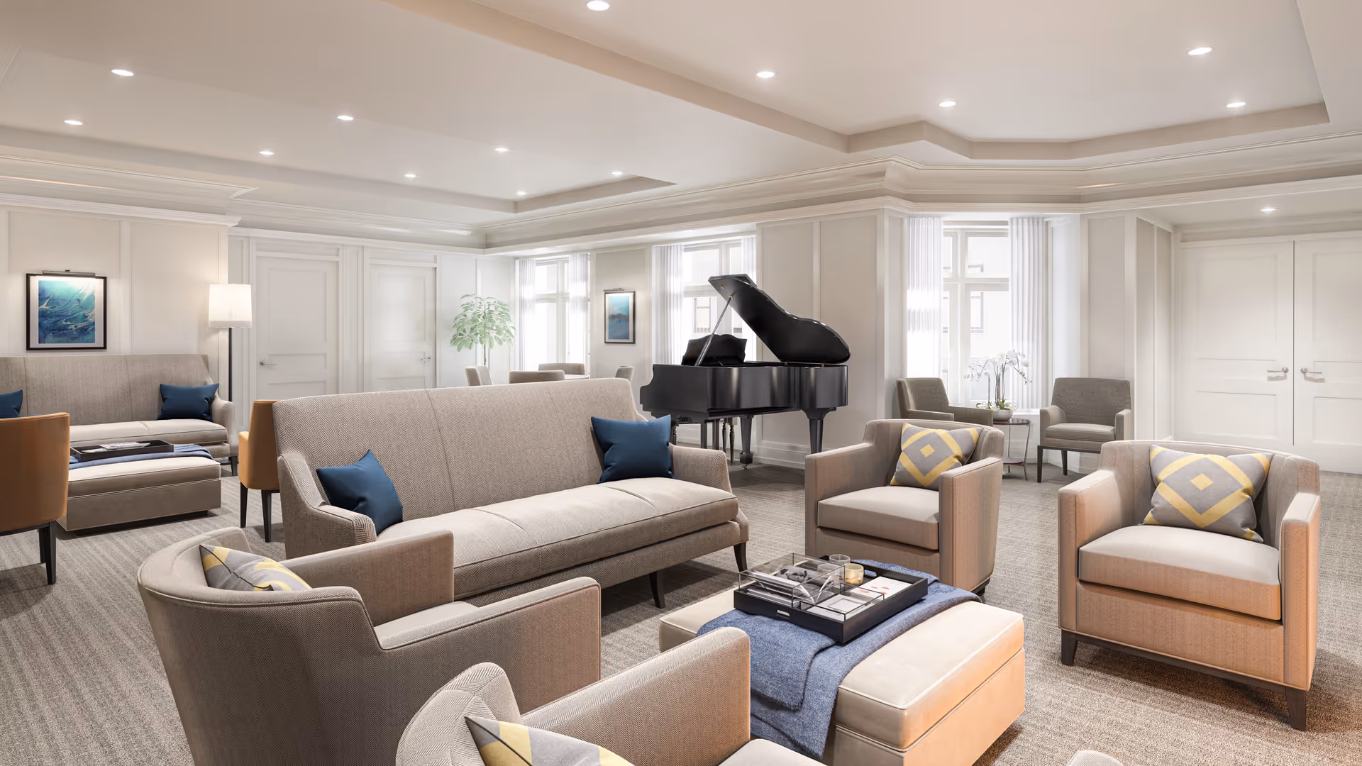A spacious and well-lit living room with beige and gray upholstered sofas and armchairs arranged around a central ottoman with a tray on top. There is a black grand piano near the windows, and the room features soft carpeting, recessed ceiling lights, and light-colored walls with decorative molding. Several framed artworks and a floor lamp are visible, creating a comfortable and elegant atmosphere.