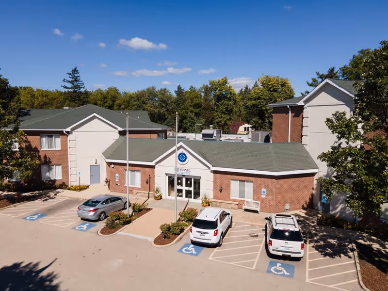 Aerial view of The Pointe at Eastgate's entrance, featuring a brick facade, green roof, and accessible parking spaces.