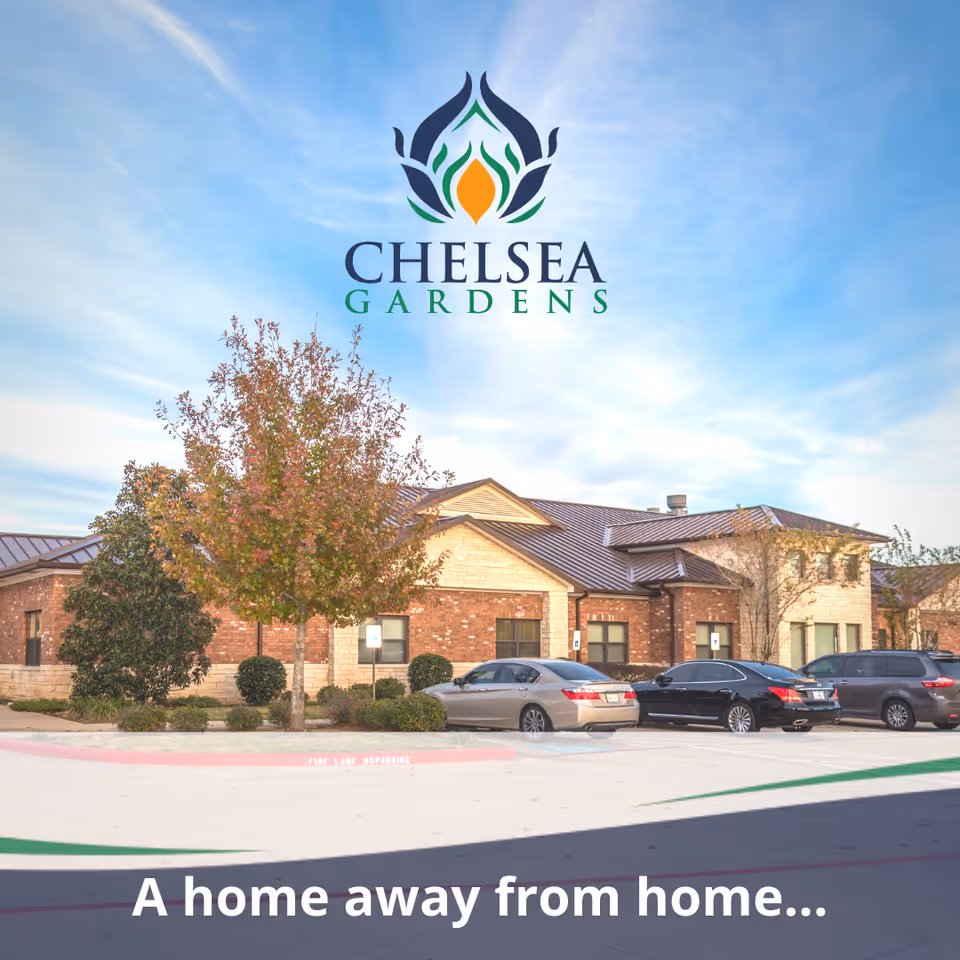 Exterior view of Chelsea Gardens Skilled Nursing & Rehab Center building with a parking lot in front, several cars parked, and a tree with autumn leaves. The sky is clear with some clouds.