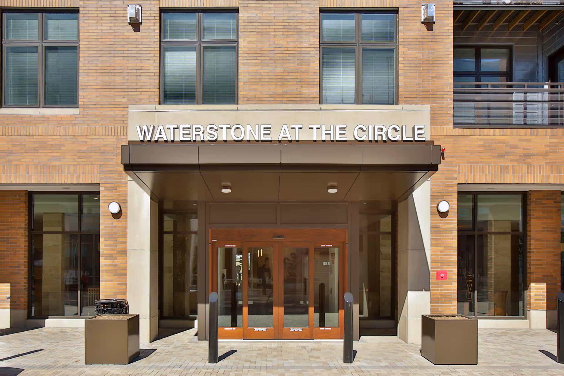 Front entrance of the Waterstone at the Circle facility with large glass doors, brick exterior walls, and the facility name displayed above the entrance.