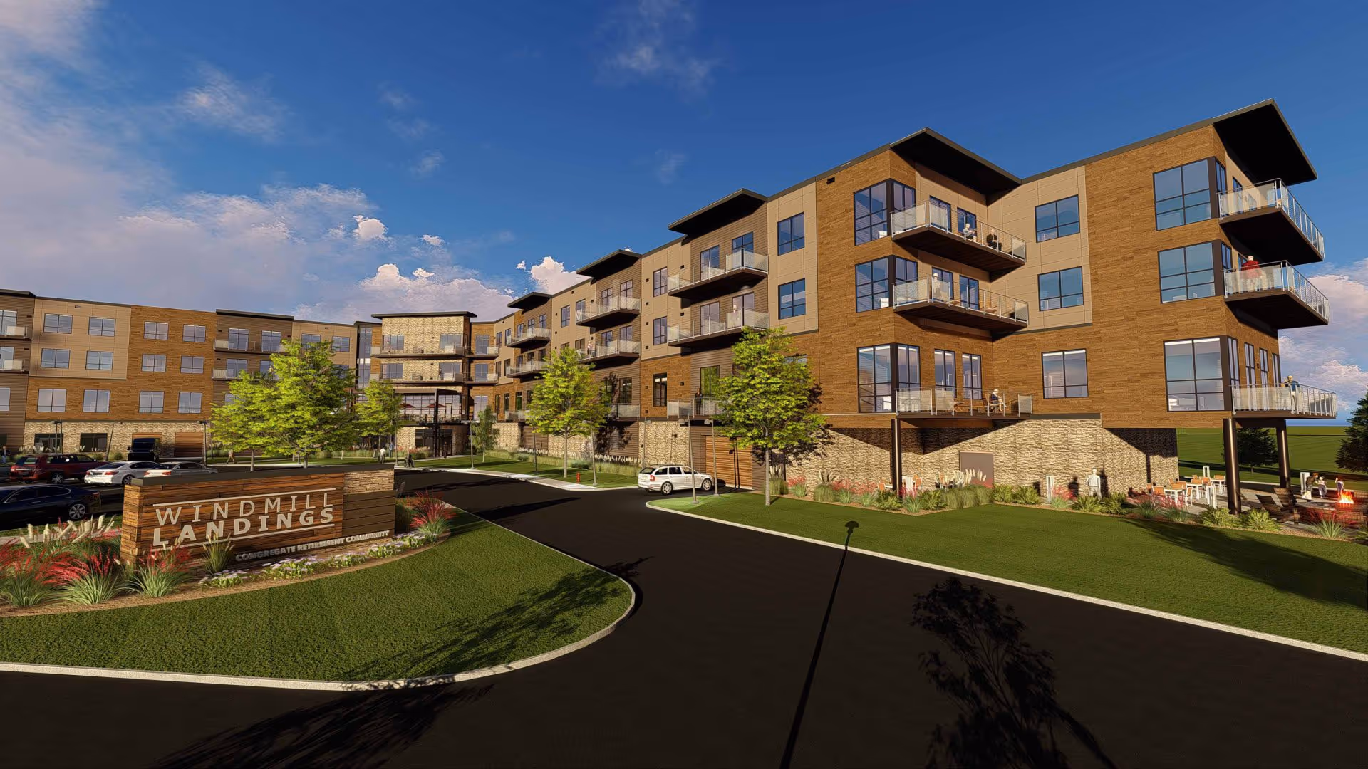 Exterior view of a modern multi-story senior living facility named Windmill Landings, featuring large windows, balconies, landscaped greenery, and a parking area under a partly cloudy blue sky.