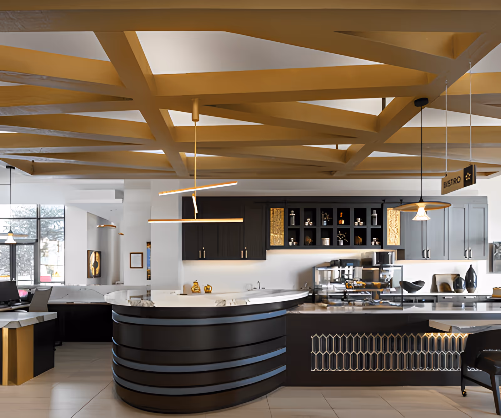 Modern kitchen area with a curved black island featuring a white marble countertop, pendant lights hanging from a ceiling with a geometric wooden beam design, black cabinetry with open shelves displaying decorative items, and a glass display case on the counter.